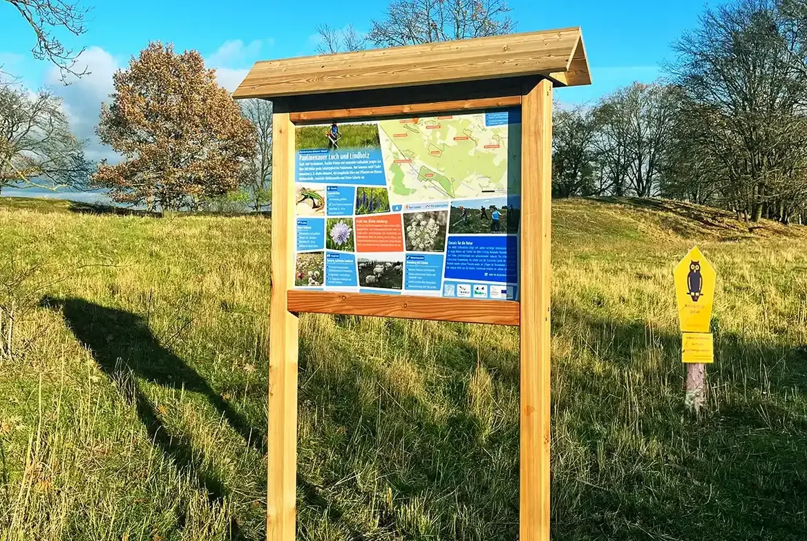 Infotafel aus Lärchenholz mit Satteldach in offener Landschaft