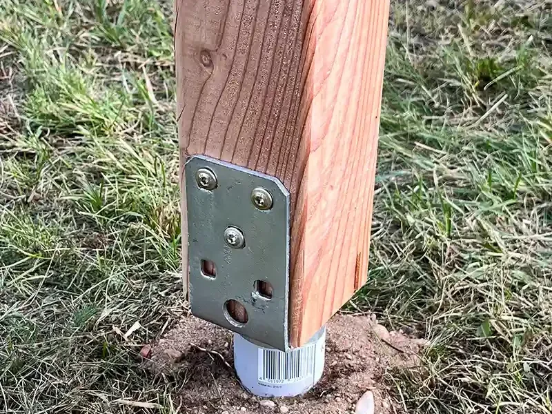 Holzpfosten einer Outdoor-Infotafel, verschraubt in einer verzinkten Bodenhülse im Erdreich.